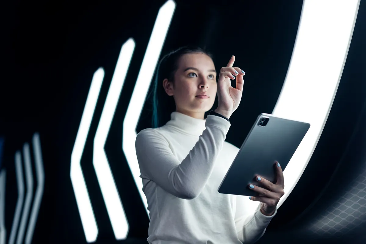 Profissional jovem usando tecnologia futurista com tablet, simbolizando as habilidades do futuro com IA.