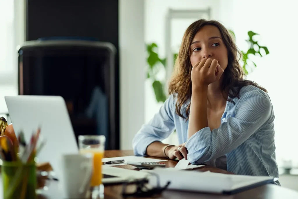 Profissional pensativa no trabalho, representando o impacto do absenteísmo no trabalho nas empresas.
